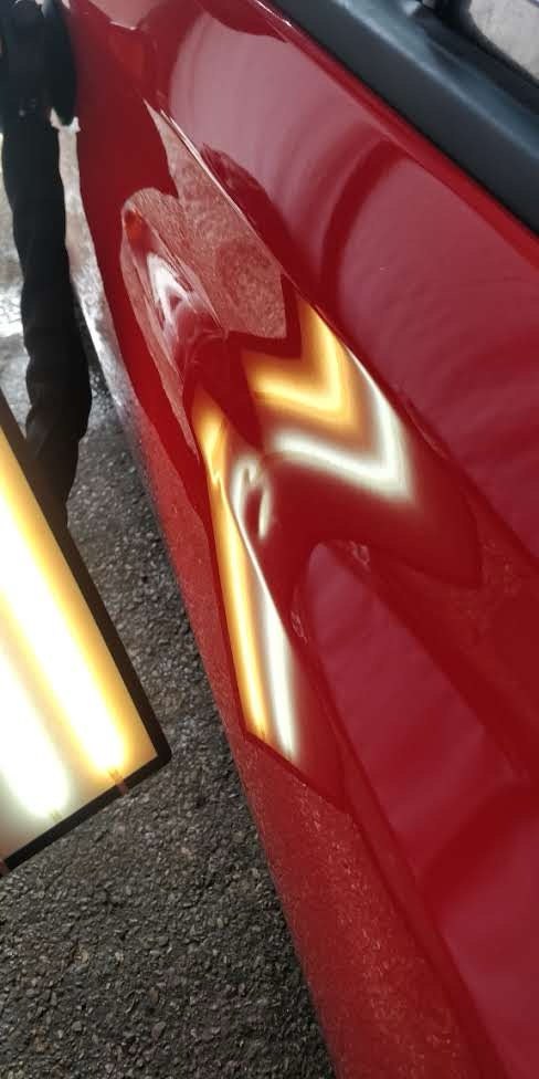Red car door crease dent before PDR